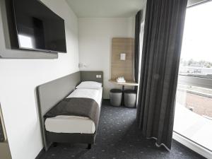 维也纳新村B&B HOTEL Wiener Neudorf的一间卧室设有一张床、一台电视和一个窗口。