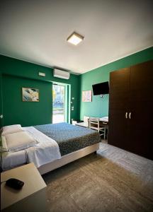 托莱港阿尔博尔格意大利酒店的一间卧室设有绿色的墙壁、一张床和一张桌子