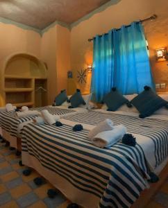 梅尔祖卡RIAD dar POUBLANC的配有蓝色窗帘的客房内的两张床
