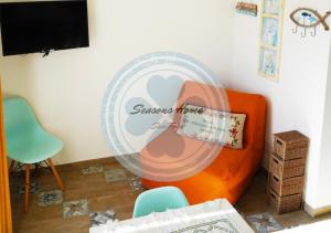 新福卡Seasons Home San Foca的带橙色椅子和风扇的客房