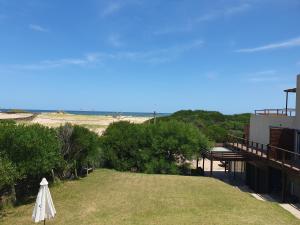 埃斯特角城Hotel Playa Chihuahua的带有伞的草坪和背景海洋