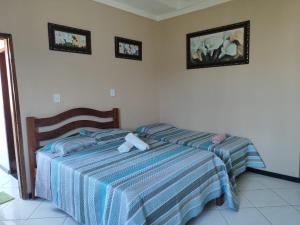 阿拉卡茹Pousada Bem-te-vi的卧室配有两张床,墙上挂有两张照片
