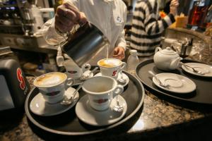 托莱港阿尔博尔格意大利酒店的把咖啡倒进柜台上的两个杯子里的人