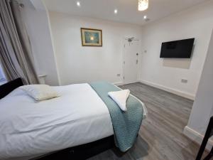WansteadElegant 2-Bedroom Double En-Suite Flat - London的一间卧室配有一张床和一台平面电视