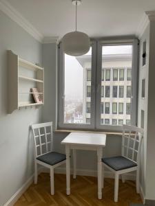 华沙Apartament 333的窗户客房内的一张白色桌子和两把椅子