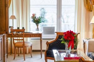 柏林Bernstein Hotel Villa Kastania的客厅配有桌子和花瓶,花朵红色