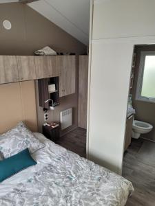 圣库隆Mobilhome tout confort, proche Saint-Malo, à 50 m de la plage et du GR34的一间卧室设有一张大床和一个卫生间