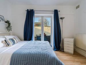 泰恩茅斯Longsands Beach, Apartment 1, Tynemouth.的一间卧室配有一张带蓝色窗帘的床和一扇窗户
