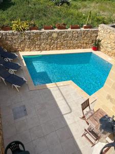 休吉让4 Bedroom Holiday Home with Private Pool & Views的一个带椅子和石墙的游泳池