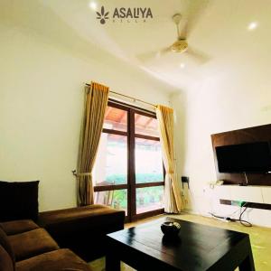 AswalapitiyaAsaliya Villa的带沙发、桌子和窗户的客厅