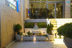 埃尔比勒Soulmate Hotel Erbil的人行道上一座建筑,上面有喷泉和盆栽植物