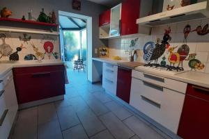 卡斯特拉韦迪藏La maison bleue de Doudou - coeur de village的厨房配有红色和白色的橱柜,墙上挂着鸡
