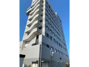 泉佐野Hotel New Yutaka - Vacation STAY 35249v的一座高大的灰色建筑,背后是蓝天