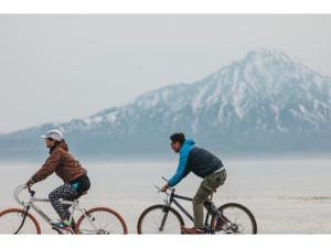 稚内THE STAY WAKKANAI - Vacation STAY 40679v的两个男人骑车在靠近水面的海滩上