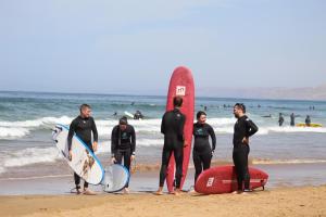 塔哈佐特Welle Surf Morocco的一群人站在海滩上,有冲浪板