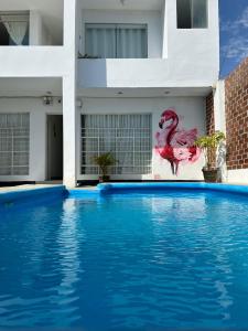 帕拉卡斯Hostel Killamoon Centro的一座带火烈鸟绘画的建筑前的游泳池