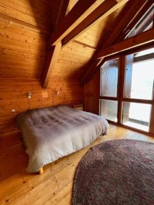 Villard-ReculasChalet d'architecte-Alpe d'Huez 9p- 4ch- 1bureau的木制客房的一张床铺,设有大窗户