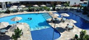 伊波茹卡Flat com vista para piscina principal的一个带遮阳伞和工作人员的大型游泳池