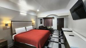 休斯顿Scottish Inn & Suites Sam Houston Parkway的酒店客房配有红色的床和沙发