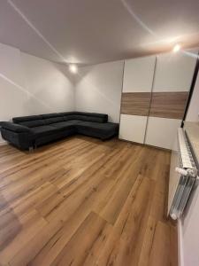 卢布林Piasecki Apartamenty的一间设有黑色沙发和木地板的客房