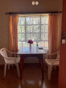MeruJungle Green Resort, Kiutine的餐桌、两把椅子和窗户