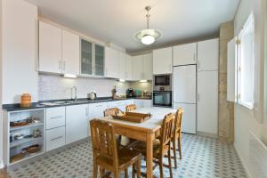 加亚新城Estrela de Gaia Apartments的厨房配有白色橱柜和木桌及椅子