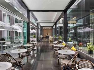 奥克兰索菲特奥克兰高架桥港酒店的餐厅设有桌椅和窗户。