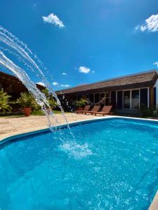 圣米格尔-杜戈斯托苏Noah Hostel & Chale的一座房子前面的游泳池,喷泉