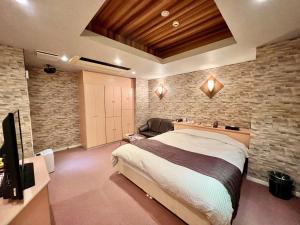 武雄市SKY Lmine Takeo LOVEHOTEL的一间卧室设有一张大床和石墙