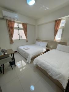 金宁乡斟酒园的一间卧室配有两张床、一张桌子和两个窗户。