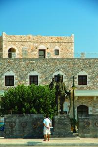 阿里奥波利斯埃里奥珀里斯精品酒店的站在建筑前面雕像前的人