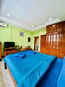 卡塔海滩BT hotel Kata Beach的一张蓝色的大床,位于带绿色墙壁的房间