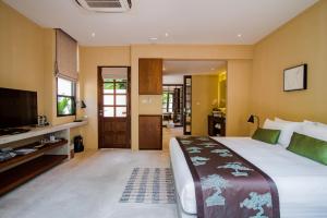 华欣Anantasila Beach Resort Hua Hin的一间卧室配有一张大床和一台平面电视