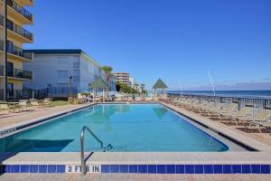 德通纳海滩海岸Sunglow Resort Condo Unit #802的一个带椅子的游泳池,背景是大海