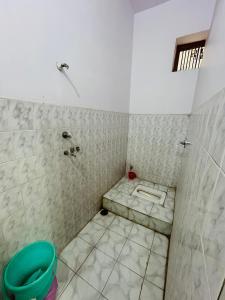 瓦拉纳西Satsang Lodge的带淋浴的浴室,铺有瓷砖地板。