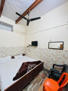 瓦拉纳西Satsang Lodge的一间卧室配有一张床和一张橙色椅子