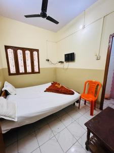 瓦拉纳西Satsang Lodge的一间卧室配有一张床和一张橙色椅子