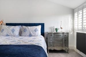 科尔切斯特Priory Farm Cottage的卧室配有蓝色和白色的床以及床头柜。