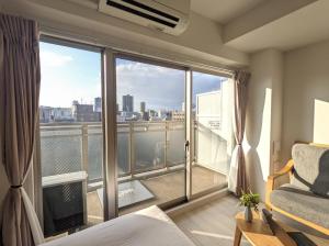 大阪ESLEAD HOTEL Osaka Tsuruhashi的一间卧室设有市景阳台