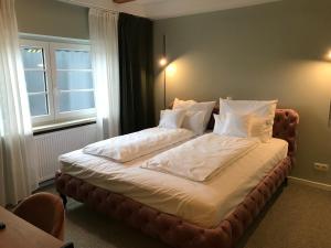 施罗本豪森Lèvres Hotel的卧室内的一张带白色床单和枕头的床