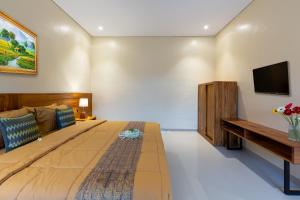 乌布Rahayu Hanoman Ubud的卧室配有一张大床,墙上配有电视