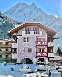 卡纳泽伊Dolomiti Luxury Mountain View的一座大粉红色的建筑,背景是一座山