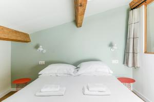 佩尔蒂Les Nids de la Diane - Appart'Conforts的一间卧室配有白色的床和两张红色椅子