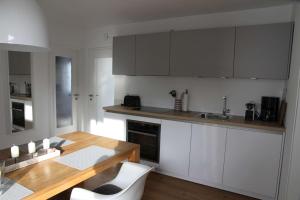 格吕克斯堡Ferienwohnung Strandgut的厨房配有白色橱柜和木桌