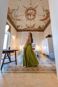 卡斯泰拉马莱Costamante Suites & Spa的站在房间里穿着绿色衣服的女人