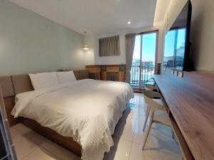 安平区安平商旅Choona Hotel Anping的一间卧室配有一张床和一张书桌,并设有一个阳台
