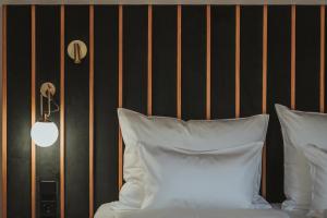 BrixenArthotel Lasserhaus的一张带白色枕头的床,旁边是黑色的墙壁