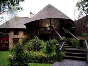 比勒陀利亚Isiphiwo Village Accommodation Venue and Spa的一座带茅草屋顶和楼梯的大房子