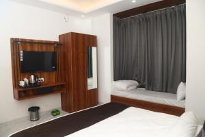 大诺伊达MK Regency的一间卧室配有一张床、一台电视和一面镜子