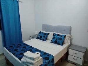 喀巴里特Highgrace Apartments Cabarete Center, whit POOL的一间卧室配有带蓝色窗帘和毛巾的床